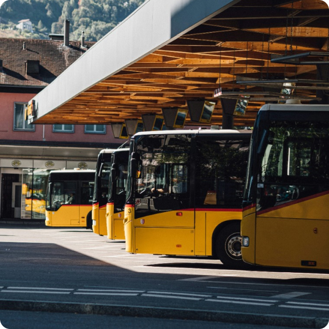 Autobus jaunes alignés à une station de transport sous une structure en bois.