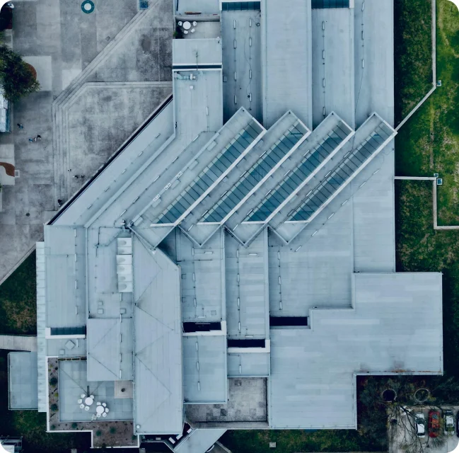 Vue aérienne d’une usine avec un toit en forme géométrique, entourée de verdure.