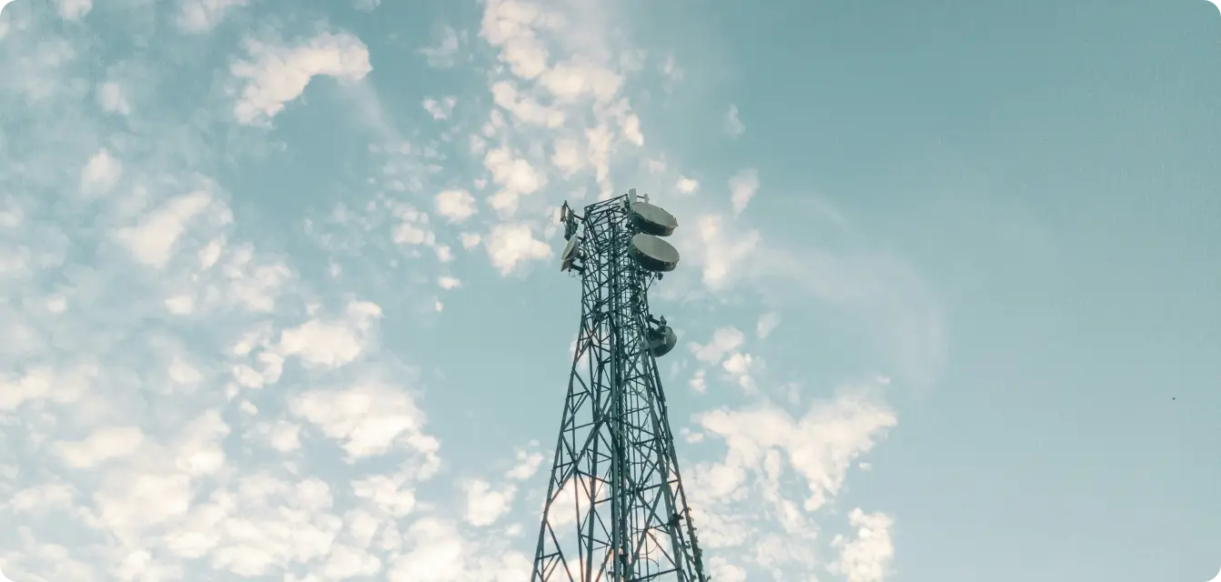 Antenne de communication métallique sous un ciel bleu avec des nuages.